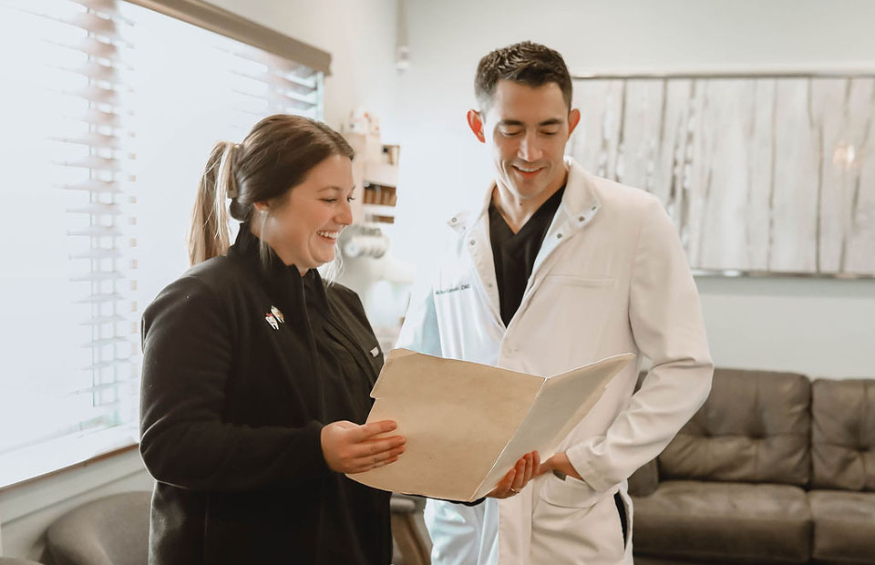 Sparks, NV dentist Dr. Kanellis and staff member smiling while reviewing some paperwork.
