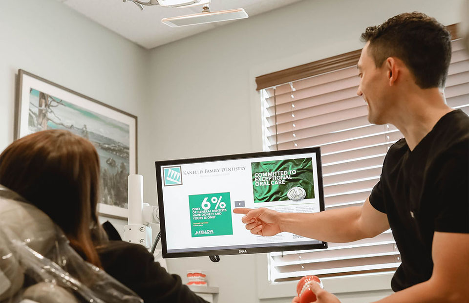 Sparks, NV dentist Dr. Kanellis pointing at a computer screen while consulting a patient.