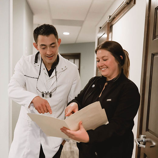 Sparks, NV dentist Dr. Kanellis and staff member smiling while reviewing some paperwork.